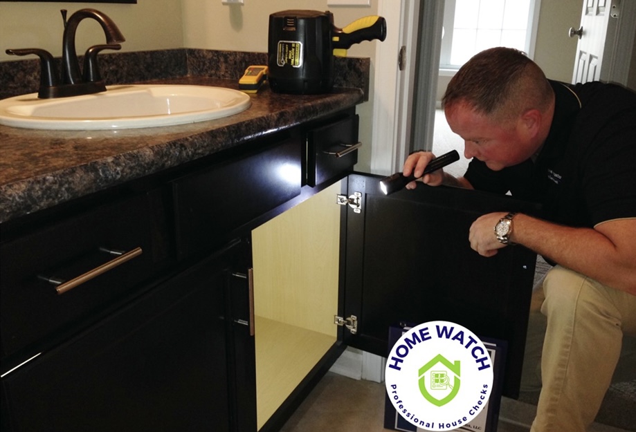 Dan Powell inspecting a bathroom sink during a home watch service visit in Rochester, NY.