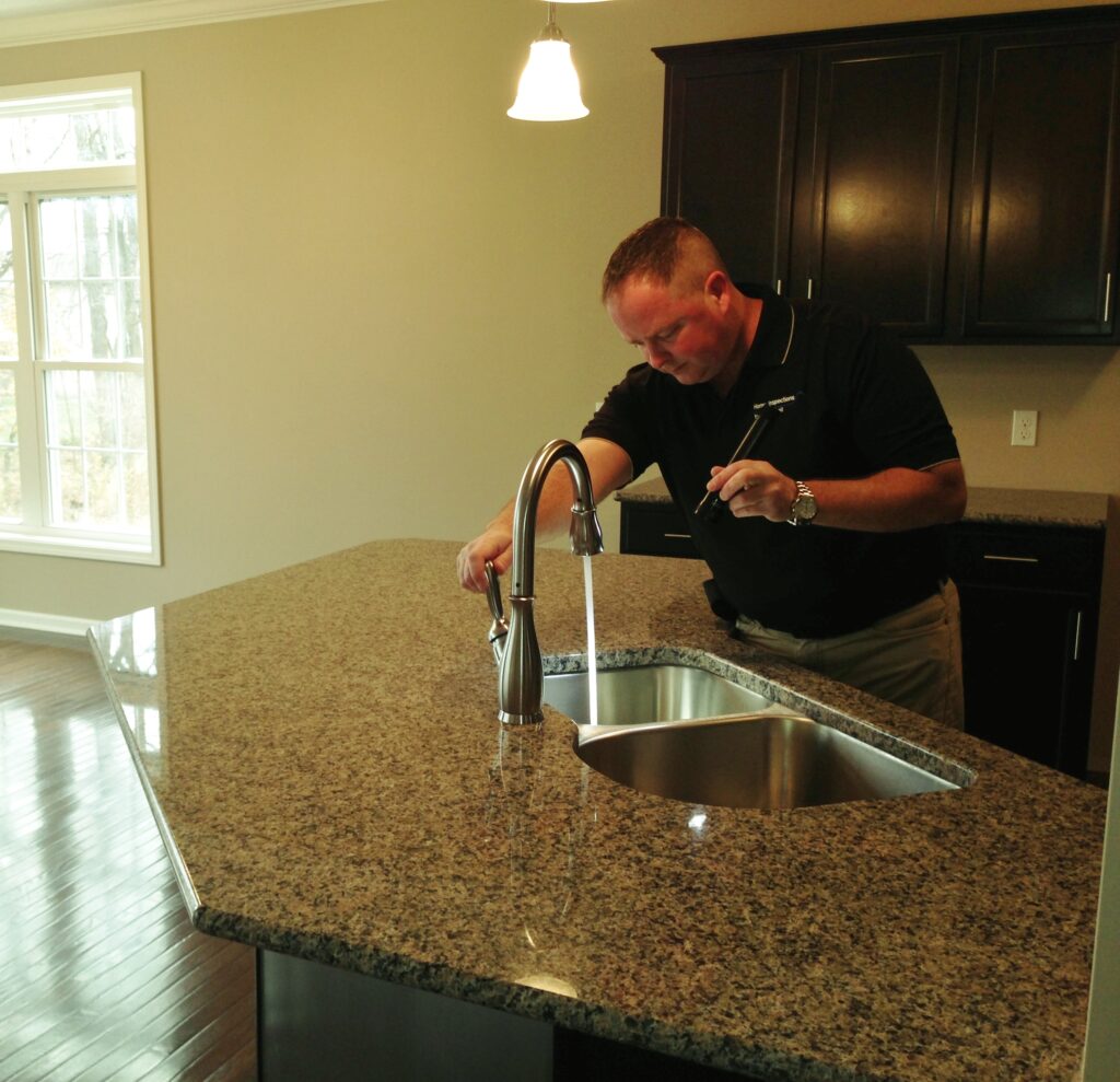 Dan Powell inspecting a kitchen sink during a home watch visit in Rochester, NY