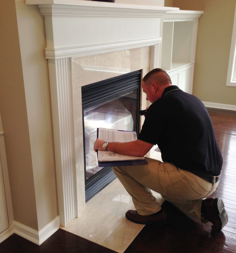 Dan Powell inspecting a gas fireplace during a home watch service visit in Rochester, NY