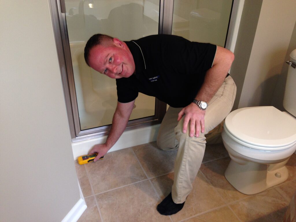 Dan Powell conducts a detailed inspection of a shower pan during a home watch visit in Rochester, NY.