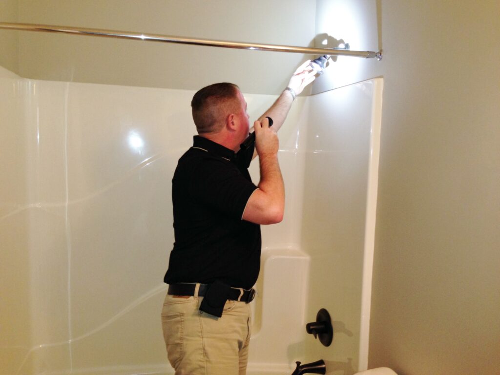 Dan Powell inspecting a shower head and faucet during a home watch service visit in Rochester, NY.