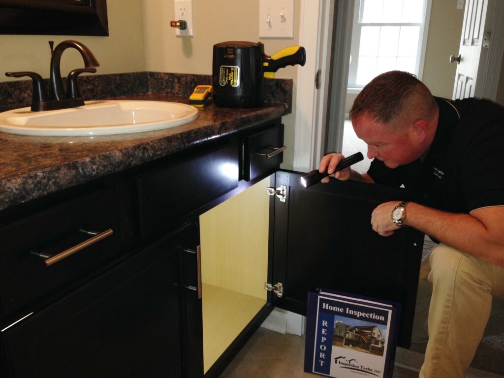 Dan Powell conducts a detailed inspection of a bathroom sink during a home watch visit in Rochester, NY.